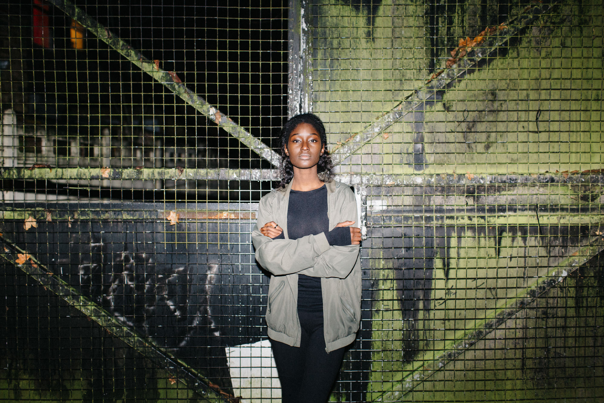 Woman standing at fence with arms crossed