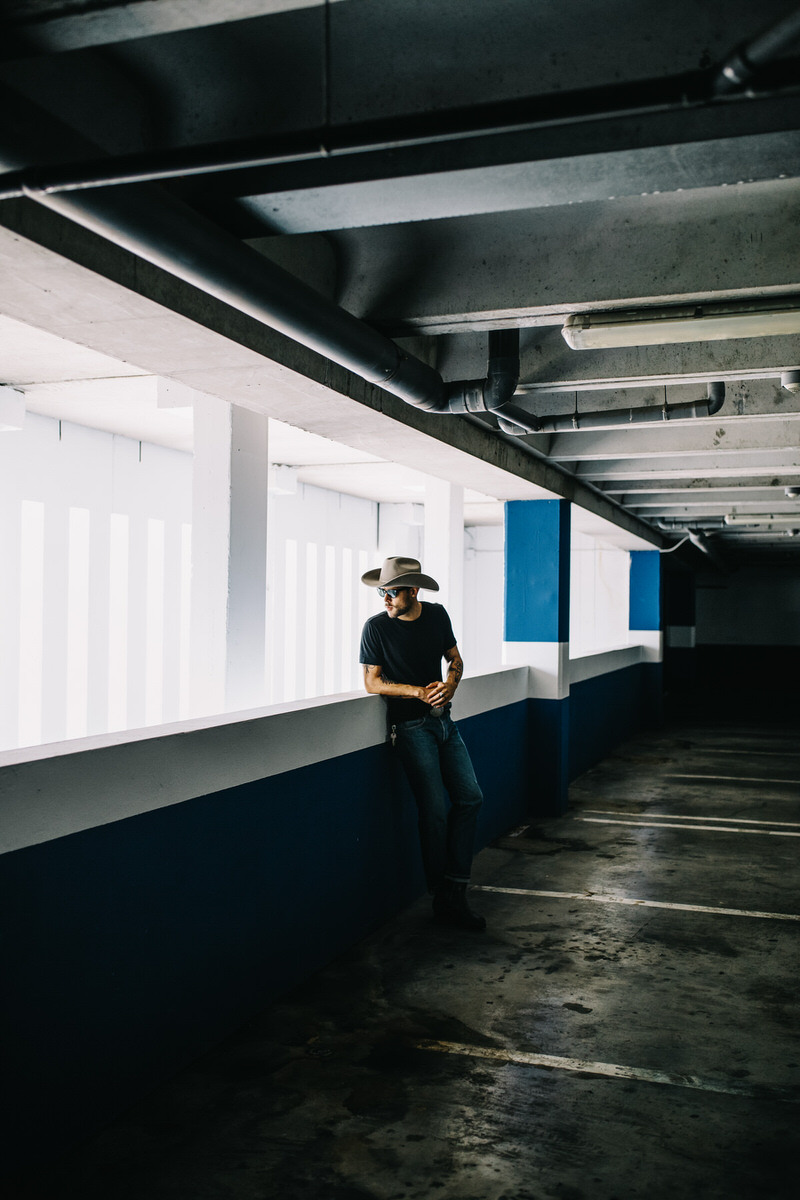 Modern man in hat standing on parking