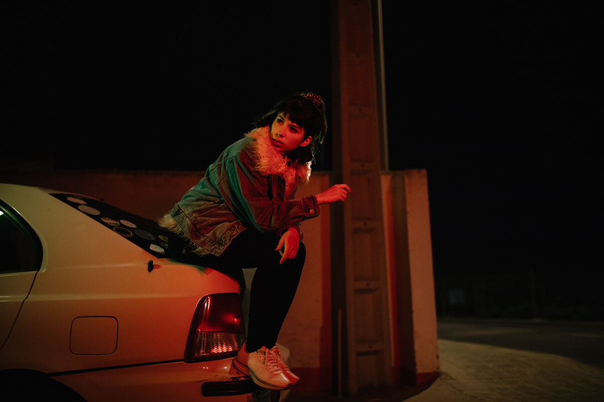 Confident model on car trunk in night