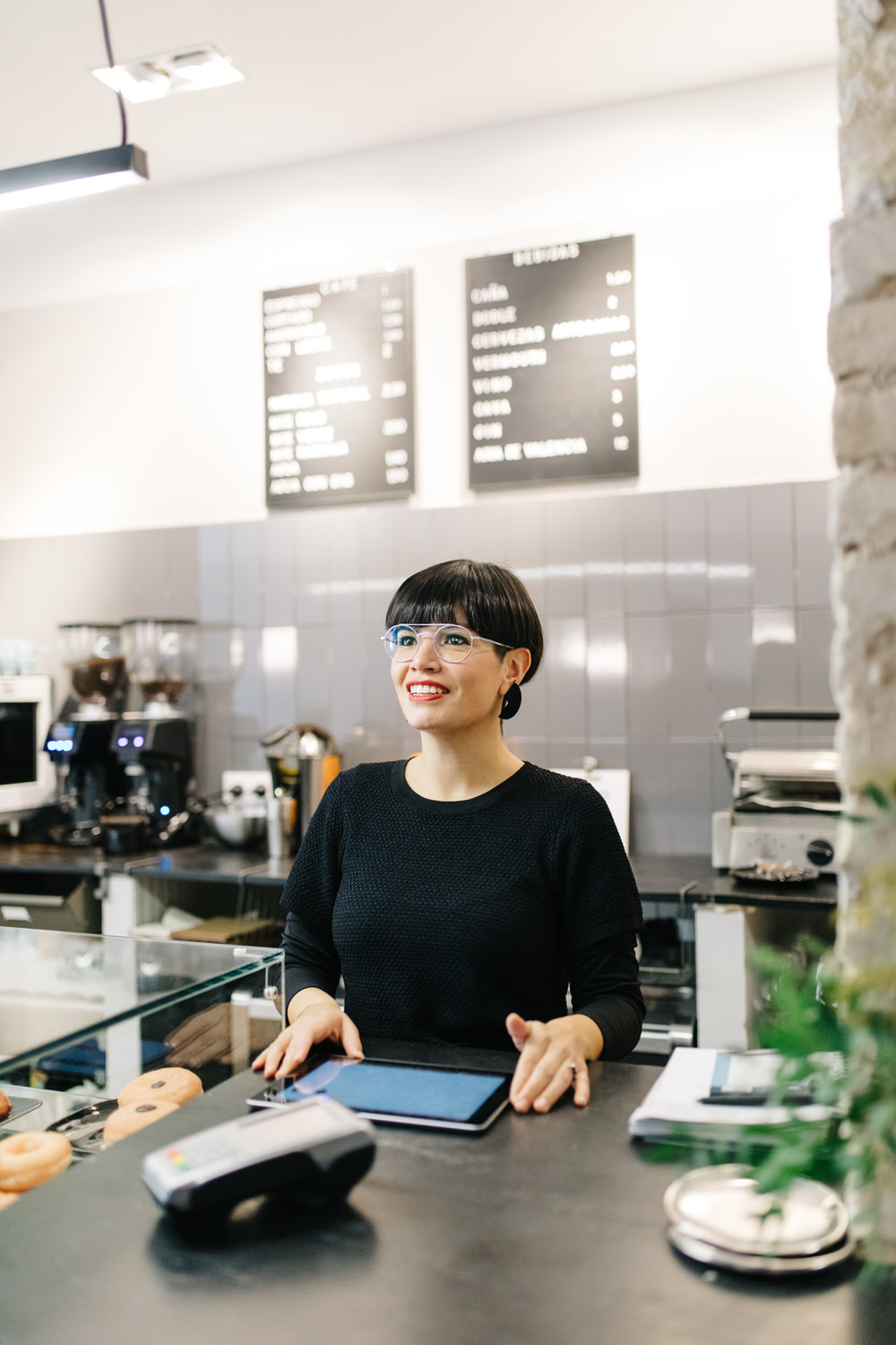 Smiling barista using tablet near cafe counter