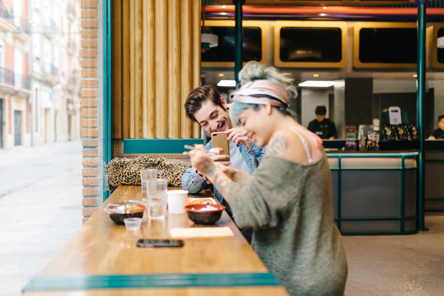 Man taking photo of laughing woman in cafe