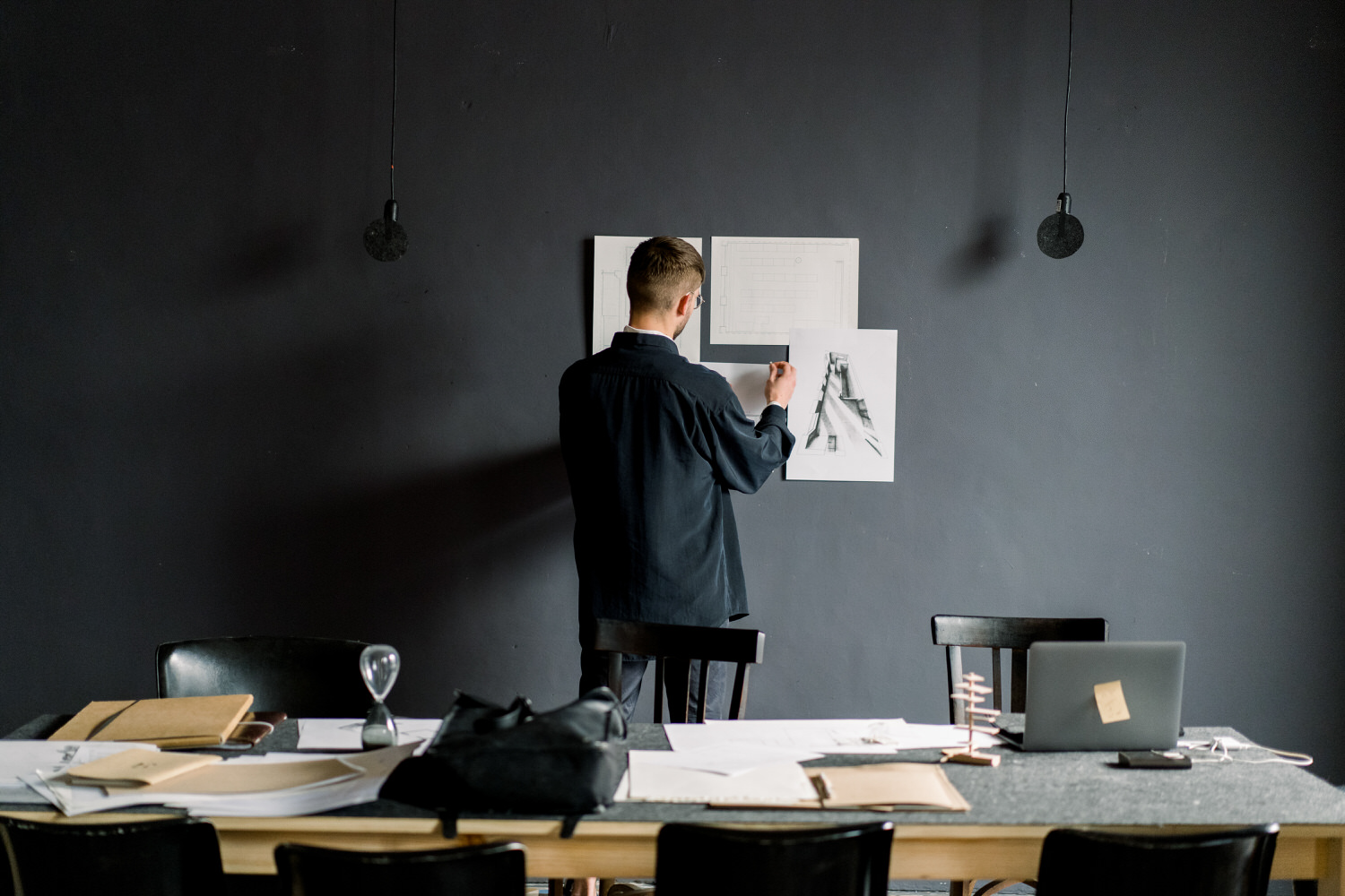 Male designer attaching drafts to wall