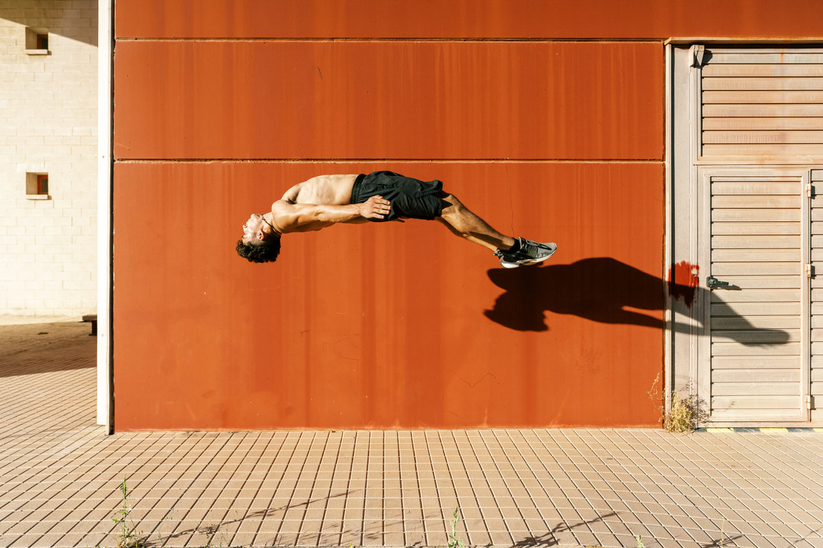 Agile sportsman doing back jump trick on street